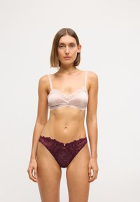 Løst blondet bralette i lys pink med justerbare stropper, parret med bordeaux blondertrusser med et blomster mønster og en dekorativ knap.