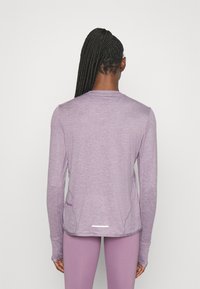 Langærmet lilla sportsbluse i let og åndbar stof. Har rund halsudskæring, sidelommer og reflekterende detalje på kanten.