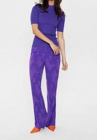 Lila ribbade topp med korta ärmar, i kombination med högmidjade lila blommiga byxor. Klänningen fullbordas med knallorange spetsiga klackar.