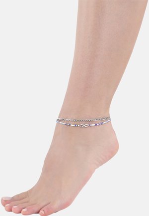 Pulsera de tobillo de plata con un diseño de cadena y acentos de cuentas coloridas, con un símbolo de infinito, llevada en un pie humano.