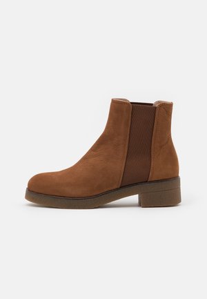Brun ruskindsankelstøvle med elastisk sidepanel, rundet tå, lav blokhælk og tekstureret gummisål.