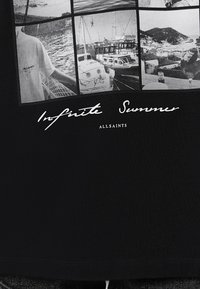 La camiseta negra presenta una serie de fotografías en blanco y negro con el texto "Verano Infinito" y el logo de "ALLSAINTS" impreso debajo.