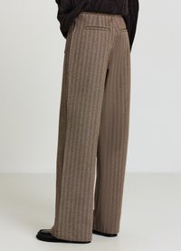 Weite Hosen mit einem strukturierten braunen Hahnentrittmuster. Verfügen über Gesäßtaschen und eine taillierte Passform. Das Material hat eine weiche Oberfläche.