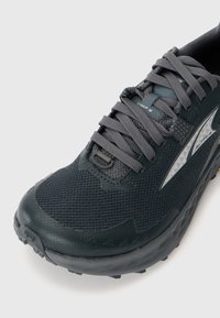 Dunkelgrauer Mesh-Laufschuh mit dickem Profil, grauen Schnürsenkeln und einem silbernen Logo-Akzent an der Seite.