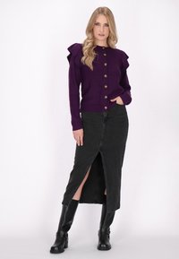 Purple knitted cardigan with ruffled shoulders, gold buttons, paired with a black denim skirt featuring a thigh-high slit and black knee-high boots.