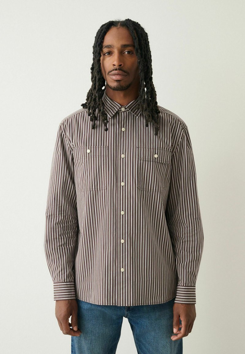 Pasiasta koszula z długim rękawem w kolorze brązowym i kremowym z kołnierzykiem, dwoma kieszeniami na piersi oraz zapięciem na guziki; gładka tkanina; prosty krój.