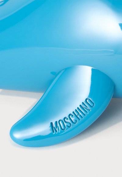 Talons de chaussure bleu brillant avec une forme courbée embossée du nom de la marque Moschino.