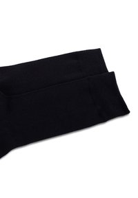 Calzini neri in cotone con una texture liscia, caratterizzati da un polsino a costine e un design della punta senza cuciture, posati piatti per mostrare il tessuto e la forma.