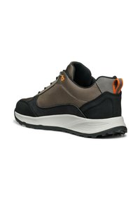 Zapatillas deportivas para hombre con una parte superior en marrón y negro, de un tejido texturizado, que presentan un acento naranja en la parte trasera y una suela de goma.