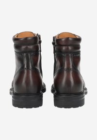 Bottes en cuir marron à la cheville avec finition texturée, surpiqûres contrastantes et bout arrondi. Dotées d'une semelle en caoutchouc robuste et d'une fermeture éclair latérale.