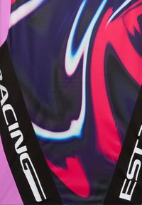 Χρωματιστό ύφασμα με αφηρημένα σχέδια σε νέον ροζ, μπλε και μωβ, μαύρες λωρίδες στα πλάγια με λευκή επιγραφή "RACING" και "EST".