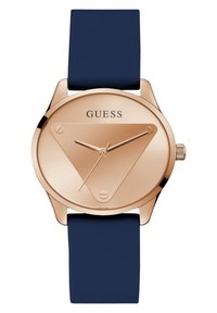 Orologio rose gold con quadrante triangolare, cinturino in silicone navy, design minimalista e movimento a tre lancette; presenta il logo 'GUESS' sul quadrante.