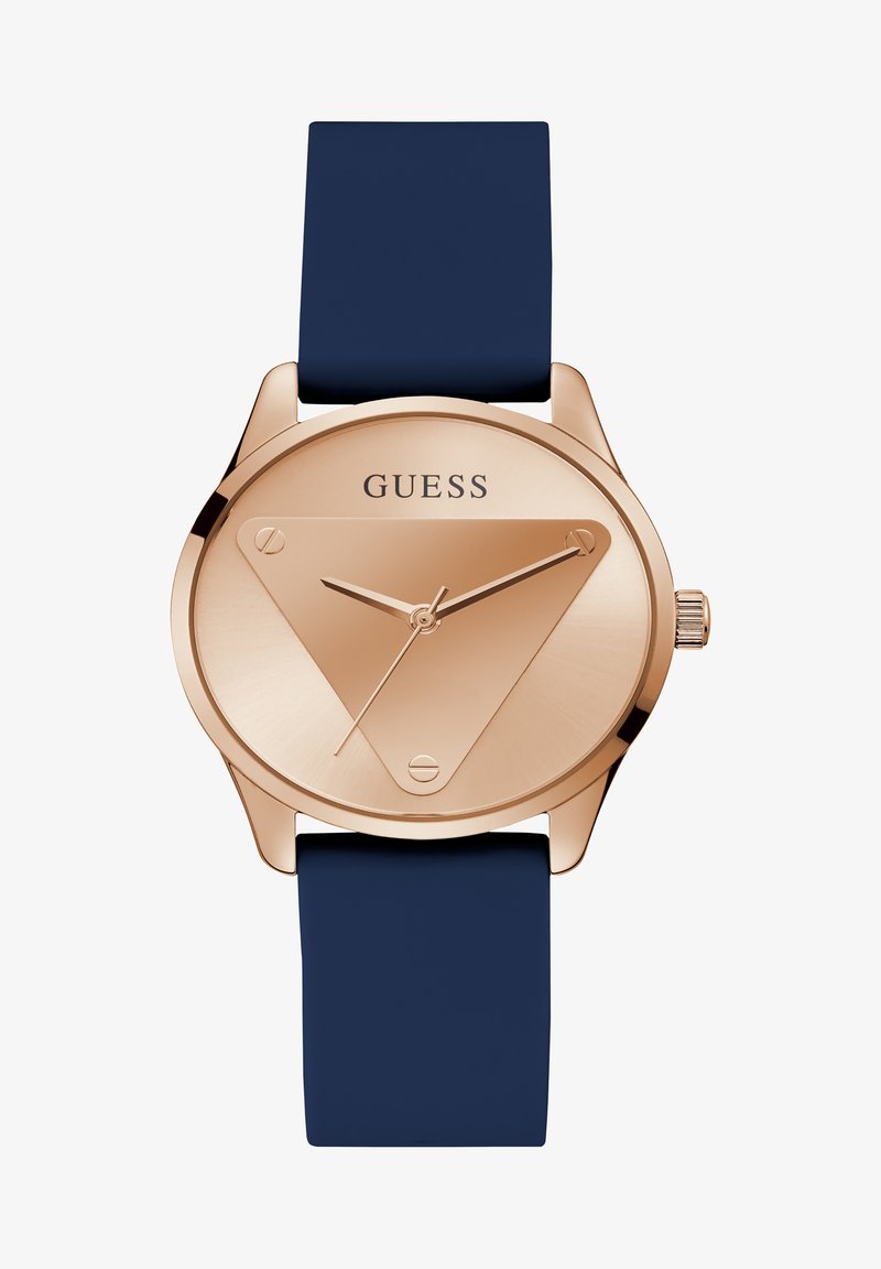 Roosa kuldne kell kolmnurga kujuga krooniga, tumesinine silikoonist rihm, minimalismist inspireeritud disain ja kolme näpu liikumine; dialil on 'GUESS' logo.