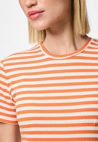 Apģērbs ar svītrotu dizainu, oranžā un baltā krāsā, ribota tekstūra, īsas piedurknes, apaļa kakla izgriezuma forma. Uzsvars uz augšējo daļu.