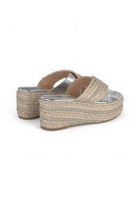 Sandales à plateforme en cuir argenté avec un design à brides croisées, des détails en jute tissé et une semelle texturée. Hauteur notable et accents métalliques.