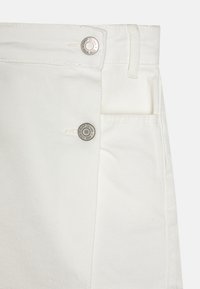 Vita denimshorts med knäppning, framfickor och en slät yta, med en subtil glans och kontrasterande sömdetaljer.