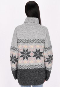 Oversized grijze gebreide trui met een hoge kraag, voorzien van een winterpatroon in zwart, roze en beige over het middelste gedeelte en de mouwen.