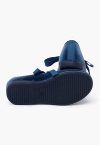 Zapatos de color azul marino con una textura aterciopelada, suela de goma plana y dos correas de tela. El diseño presenta una puntera redonda y costuras limpias.