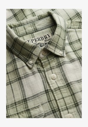 Chemise à carreaux verts et blancs avec col boutonné et étiquette de marque "Superdry" visible à l'intérieur du col.