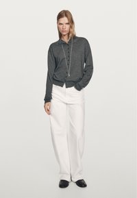 Chemise grise à manches longues avec un col, associée à un pantalon large blanc et des chaussures noires. Design simple avec une coupe décontractée.
