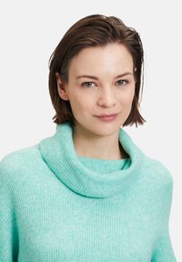 Coltrui in licht muntgroen, gebreide textuur, relaxte pasvorm, met een geribde kraag en zachte, comfortabele stof.
