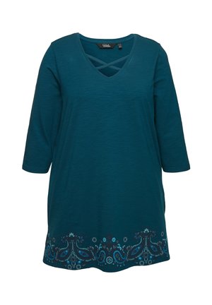 Tyrkysová tunika s výstřihem do V a křížovým detailem. Má 3/4 rukávy a zdobné květinové vyšívání na spodním lemu v různých odstínech modré.
