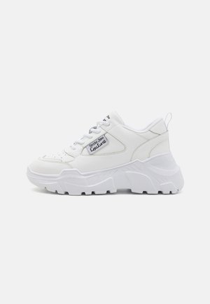 Sneaker bianco con suola chunky, superiore in sintetico liscio, punta tonda e design con lacci. Dettaglio del logo laterale e linguetta sul tallone.