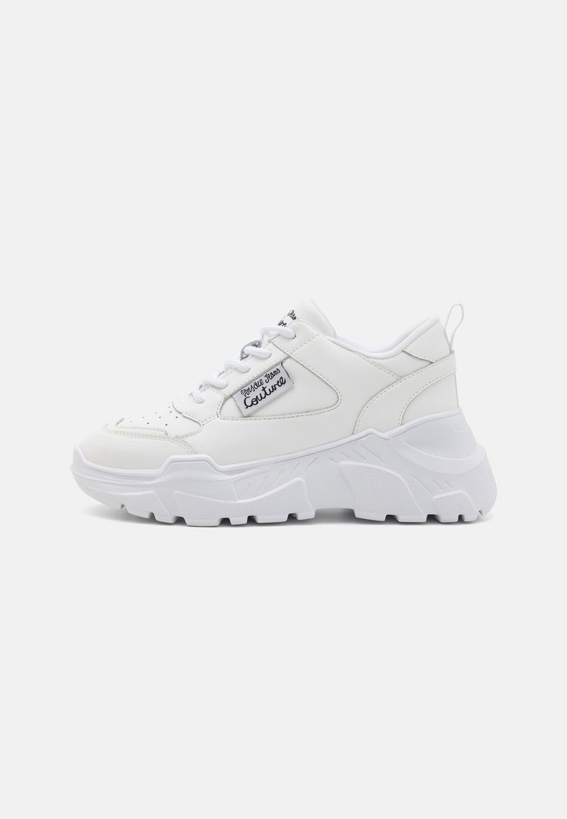 Sapatilha branca com sola grossa, parte superior sintética suave, biqueira redonda e design com atacadores. Detalhe do logo na lateral e alça na parte de trás.