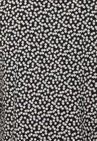 Svart tyg med tät små vita blommönster som visar fembladiga blommor jämnt spridda över ytan.