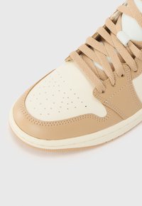 Baskets en cuir tan avec des accents crème, bout perforé, lacets texturés et détails cousus. Semelle en caoutchouc avec un léger contraste de couleur.