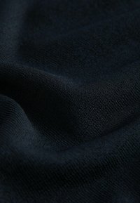 Zwarte textiel met een gladde textuur, met een subtiel geweven patroon. De stof heeft een zachte val en lijkt gemiddeld zwaar te zijn.