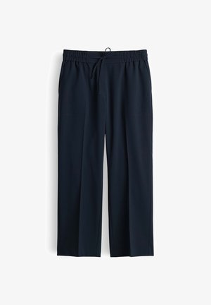 Pantaloni da uomo neri con vita elastica, coulisse regolabile e gamba dritta, esposti appesi su sfondo bianco.