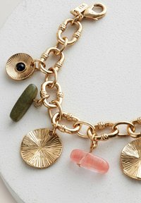 Guldtonet armbånd med kædelinks, strukturerede runde charms og farvede stenarangementer i grøn, sort og pink.
