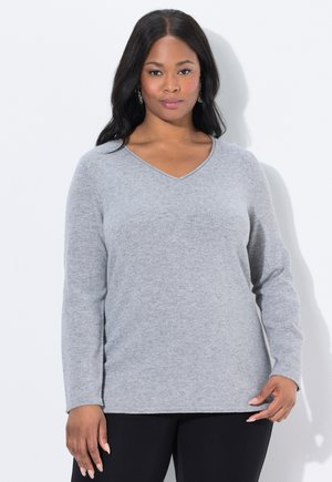 Pull gris à manches longues et col en V, en tissu tricoté doux et texturé ; associé à un bas noir. Design minimaliste avec une coupe décontractée.