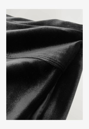 Must mustri kangas, millel on pehme tekstuur, sujuvate ja voolavate voldikutega ning korralik õmblusdetail äärel.