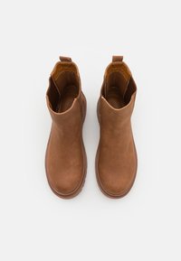 Botines marrones de cuero suave, con punta redondeada, paneles laterales elásticos y una lengüeta en la parte trasera.