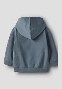 Hoodie u prigušenoj plavoj boji, napravljen od mekog, laganog materijala. Ima rebraste manžetne i donji rub, te bešavnu pozadinu.