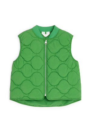 Grøn quiltet vest uden ærmer med lynlås foran og rund krave, der viser et cirkulært quiltet mønster på stoffet.