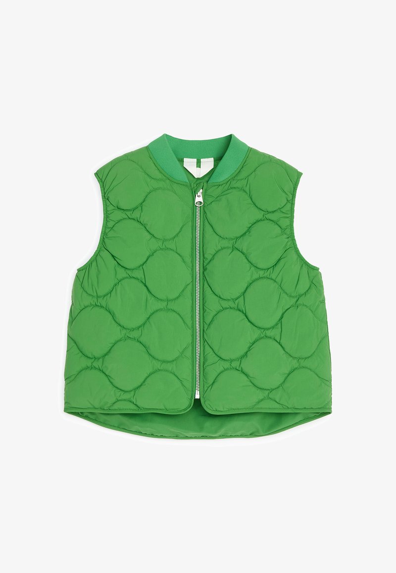 Veste matelassée verte sans manches avec une fermeture éclair à l'avant et un col rond montrant un motif circulaire cousu sur le tissu.