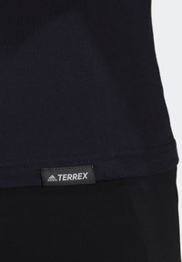 Náměsíčný modrý terrex tričko vyrobené z jemné tkaniny, s prošívaným lemem a viditelnou značkovou visačkou s nápisy "adidas" a "TERREX".