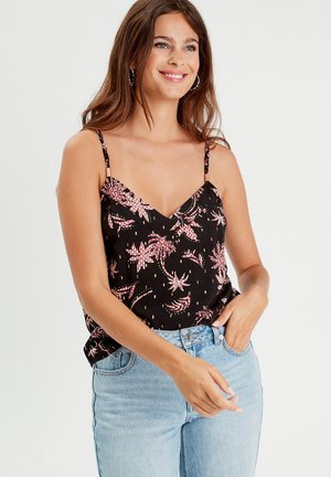 Débardeur noir avec un col en V, motif floral rose et blanc, bretelles fines et coupe ample, associé à un jean bleu clair.