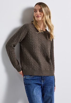Brun, struktureret striktrøje med zigzag-mønster, rund halsudskæring og ribbede manchetter og kant; båret med blå jeans.