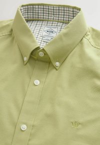 Heleroheline nööbitav särk valgete nööpidega, ruuduline sisemine kraevooder ning väike tikitud krooni logo rinnal.