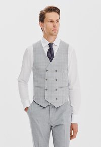 Szary kamizelka w kratę z pięcioma guzikami z przodu, z wykładanymi klapami i dwoma przednimi kieszeniami, zestawiona z białą koszulą i ciemnym, wzorzystym krawatem.