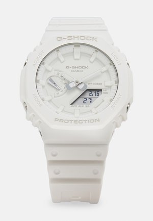 G-SHOCK horloge in witte hars met een ronde wijzerplaat, analoge en digitale displays, en een gestructureerde band. Kenmerken zijn waterbestendigheid tot 20 bar.