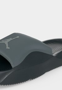 Μαύρο και γκρι σανδάλι τύπου slip-on με ανυψωμένη σόλα και ανάγλυφο λογότυπο Jumpman στο φαρδύ πάνω λουράκι.