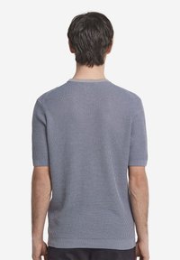 Kortärmad stickad tröja i ljusblått, med en strukturerad yta, ribbad krage och manschetter, samt en rak fåll vid midjan.