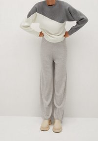 Gray and white color-blocked sweater with long sleeves, paired with light gray wide-legged pants and beige slip-on shoes. Soft texture.
