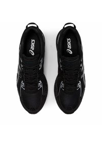 Ein Paar schwarze Asics-Laufschuhe mit grauen Akzenten, gebunden, von oben auf einem weißen Hintergrund betrachtet.