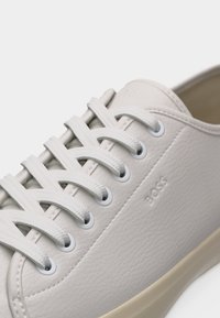 Weißer Sneaker aus Leder mit strukturierten Schnürsenkeln, die durch Metallösen geführt sind, mit dem geprägt "BOSS"-Schriftzug an der Seite.